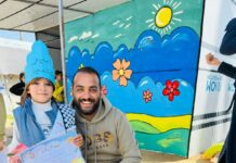 Gaza Palestinian American Association: A humanitarian message to support orphans and build hope GPAA volunteer kneeling with a young orphan child holding an appreciation certificate at a GPAA event in Gaza
